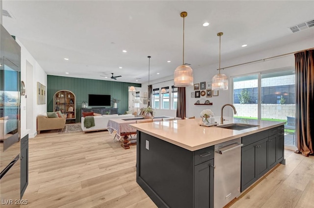 kitchen featuring light wood finished floors, a wealth of natural light, visible vents, stainless steel dishwasher, and a sink