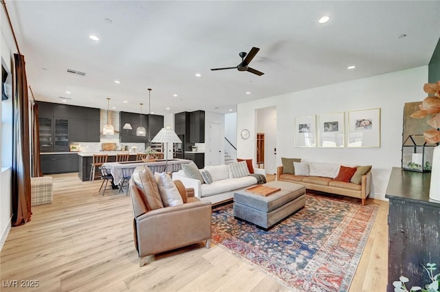 living area featuring ceiling fan, recessed lighting, visible vents, light wood-style floors, and stairway