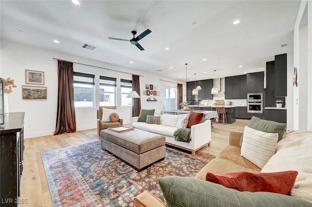 living room featuring light wood-style flooring, recessed lighting, a ceiling fan, baseboards, and visible vents