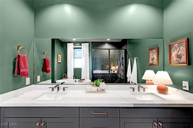 bathroom featuring double vanity, a stall shower, and a sink