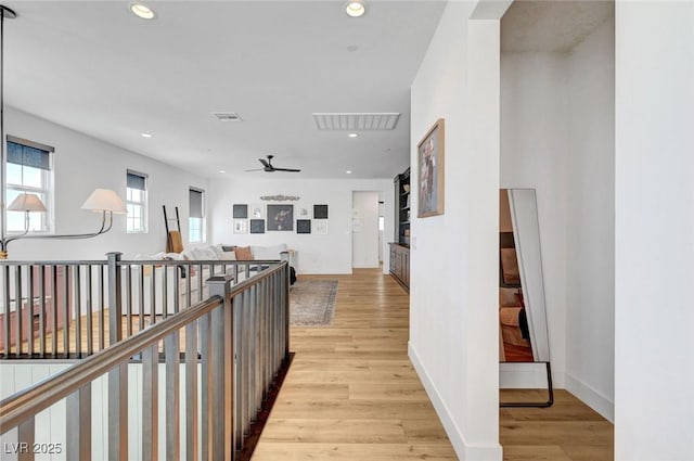 hallway featuring light wood finished floors, visible vents, and recessed lighting