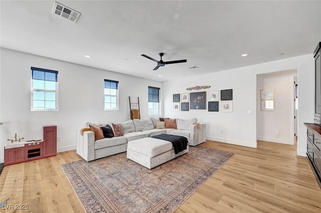 living area with light wood-style floors, recessed lighting, visible vents, and baseboards