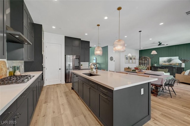 kitchen featuring light wood finished floors, stainless steel appliances, a sink, and open floor plan