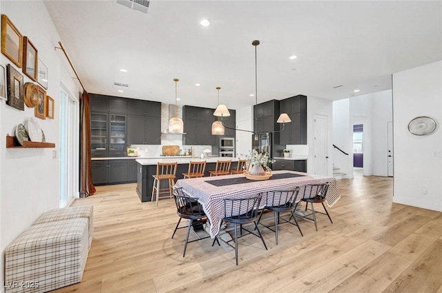 dining area with light wood-style floors, stairs, visible vents, and recessed lighting