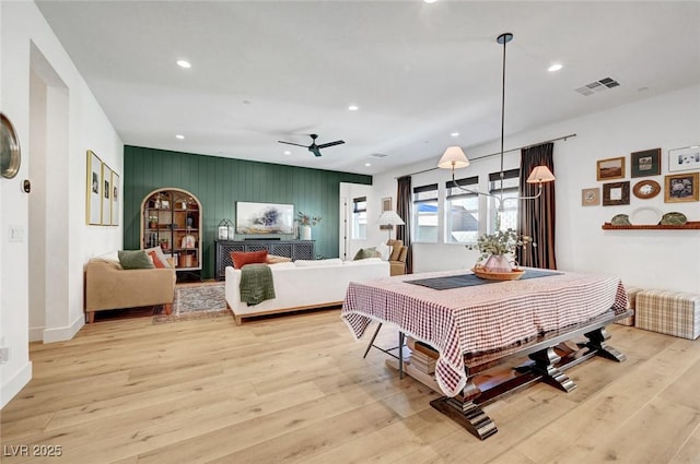 bedroom with light wood-style floors, an accent wall, visible vents, and recessed lighting