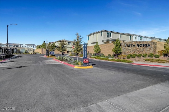 view of road featuring street lighting, a residential view, curbs, and a gated entry