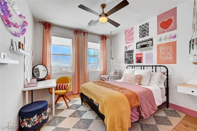 bedroom featuring visible vents, ceiling fan, baseboards, and wood finished floors