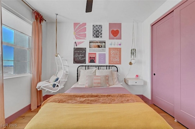 bedroom featuring light wood-style floors, a closet, baseboards, and a ceiling fan