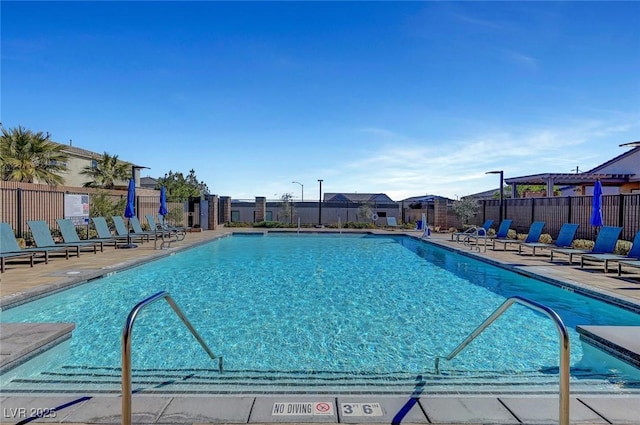 community pool with a patio area and fence