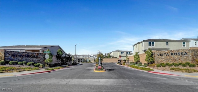 view of street featuring street lighting, traffic signs, sidewalks, a residential view, and curbs