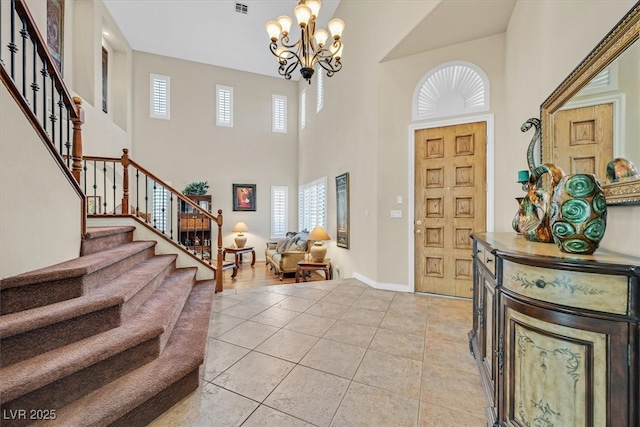 foyer entrance with light tile patterned floors, baseboards, a towering ceiling, stairs, and a chandelier