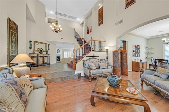 living room with visible vents, arched walkways, a notable chandelier, and wood finished floors