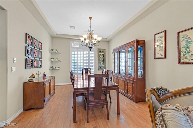 dining room featuring baseboards, visible vents, a notable chandelier, and light wood finished floors