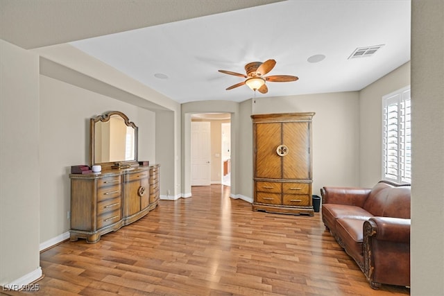 sitting room with light wood-type flooring, visible vents, arched walkways, and baseboards