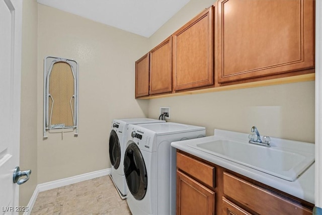 laundry room with a sink, washing machine and dryer, cabinet space, and baseboards