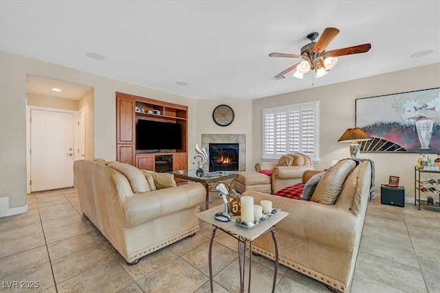 living room featuring a ceiling fan, light tile patterned flooring, a fireplace, and baseboards