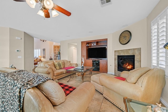 living room with light tile patterned flooring, ceiling fan, visible vents, and a tile fireplace