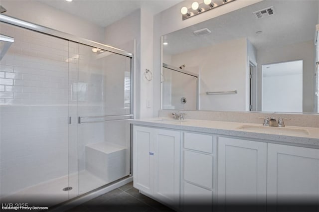 full bath with tile patterned flooring, a sink, visible vents, and a shower stall