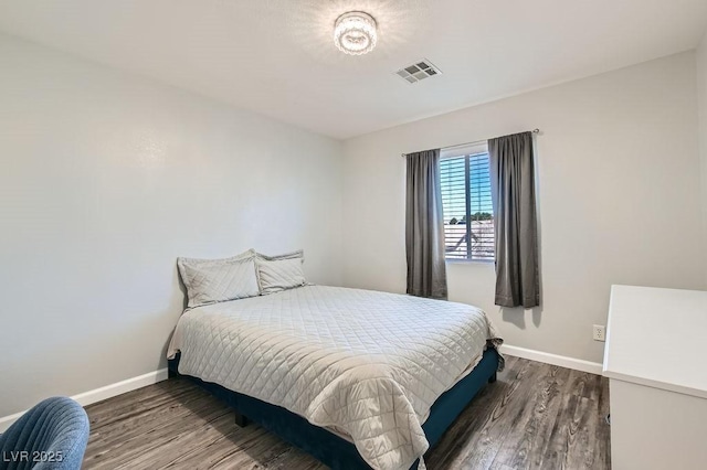 bedroom with wood finished floors, visible vents, and baseboards