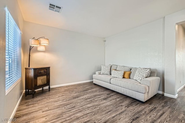 living room featuring baseboards, visible vents, and wood finished floors