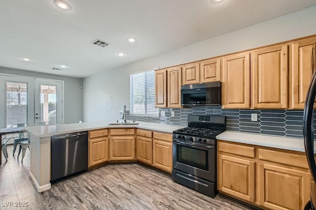 kitchen with stainless steel appliances, tasteful backsplash, visible vents, a sink, and a peninsula