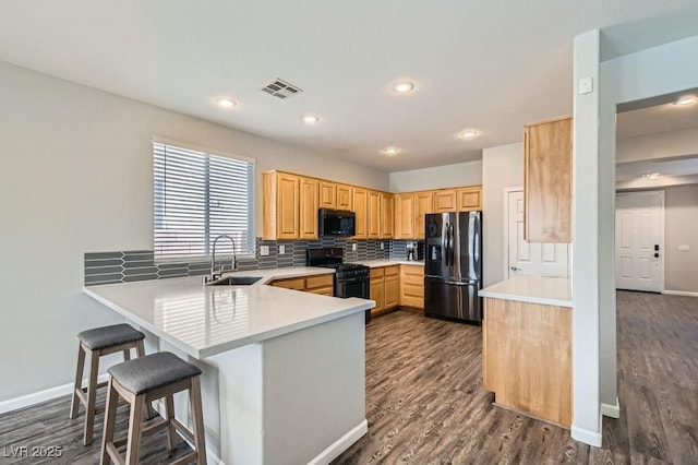 kitchen featuring visible vents, black range with gas stovetop, light brown cabinets, refrigerator with ice dispenser, and a sink