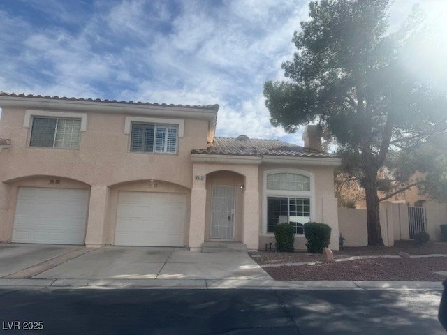 mediterranean / spanish-style house featuring a garage, concrete driveway, a tiled roof, fence, and stucco siding