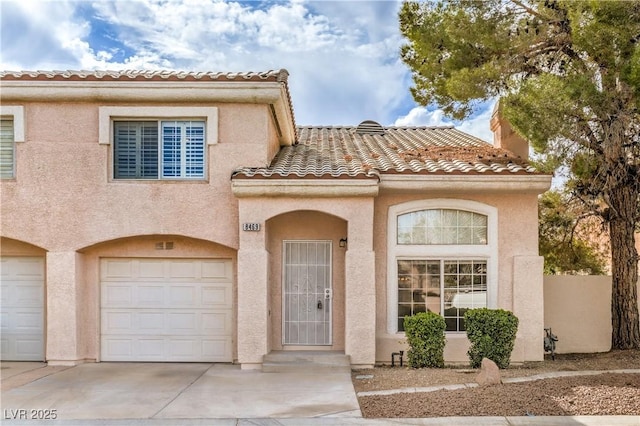 mediterranean / spanish house with a garage, a tiled roof, and stucco siding