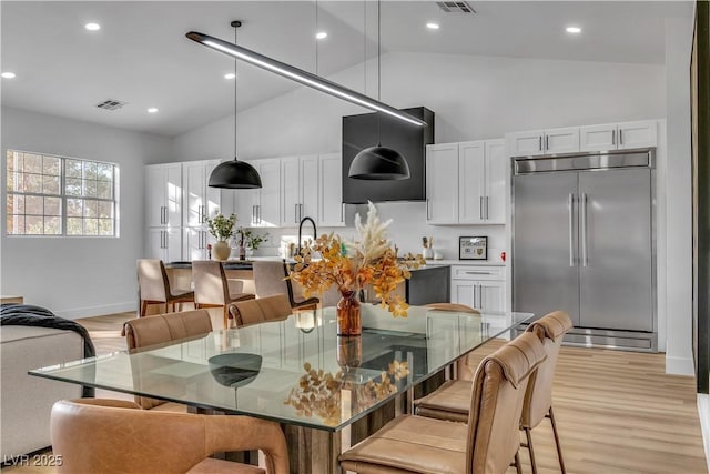 dining area with light wood finished floors, visible vents, baseboards, recessed lighting, and high vaulted ceiling