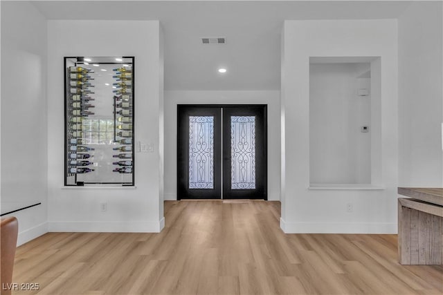 entrance foyer with visible vents, baseboards, wood finished floors, and french doors