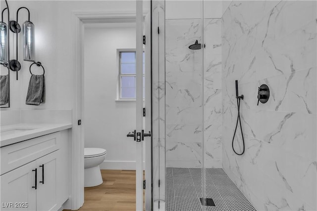 bathroom with a marble finish shower, baseboards, toilet, wood finished floors, and vanity