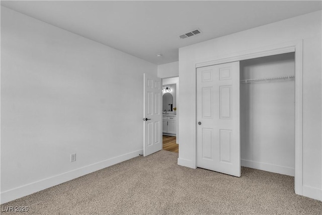 unfurnished bedroom with light colored carpet, visible vents, a closet, and baseboards