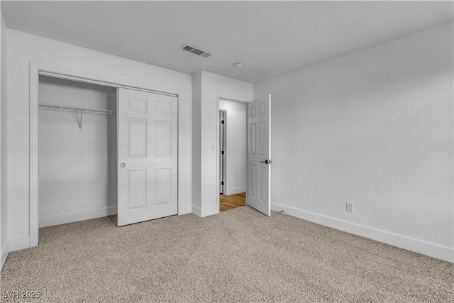 unfurnished bedroom featuring a closet, baseboards, visible vents, and carpet floors