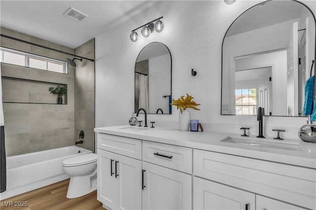 bathroom featuring a sink, visible vents, toilet, and wood finished floors