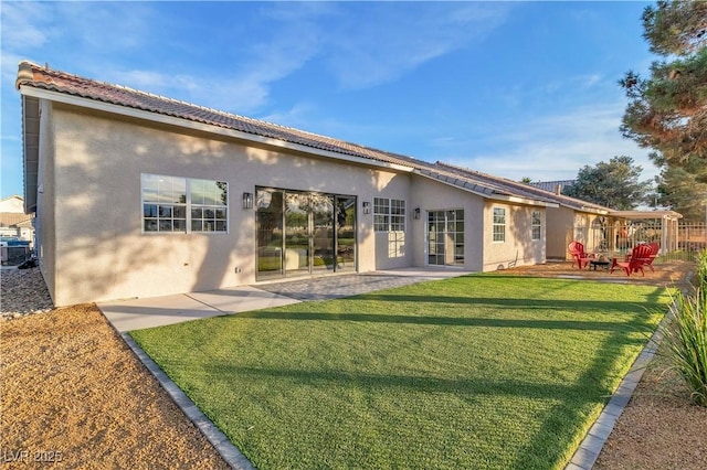 rear view of property featuring stucco siding, a patio, and a yard