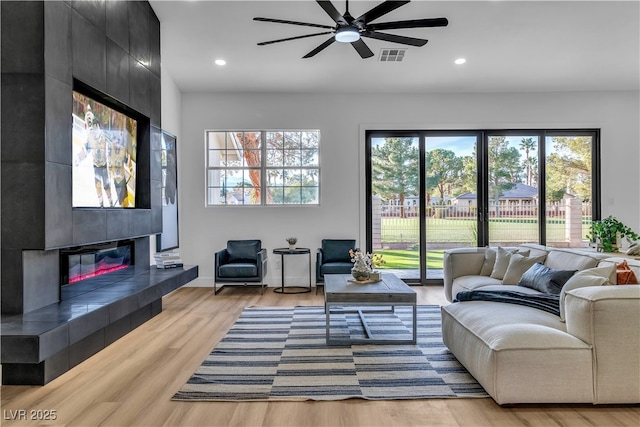 living area featuring a ceiling fan, visible vents, recessed lighting, a tile fireplace, and light wood-style floors