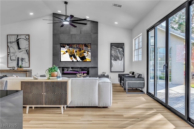 living room featuring visible vents, high vaulted ceiling, a tiled fireplace, wood finished floors, and recessed lighting