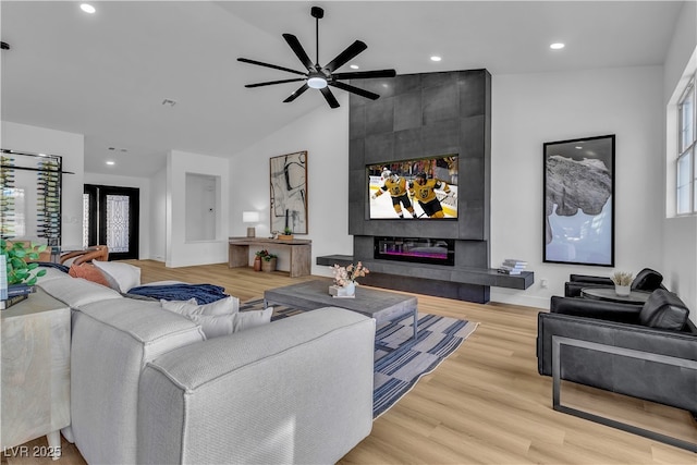 living room featuring baseboards, recessed lighting, a tile fireplace, wood finished floors, and high vaulted ceiling