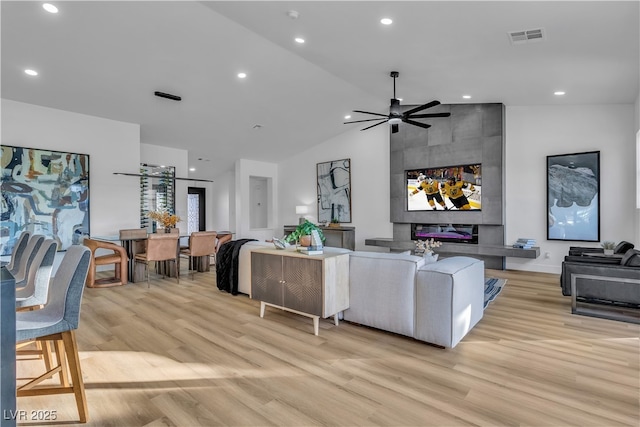 living area with visible vents, light wood-style flooring, a ceiling fan, recessed lighting, and vaulted ceiling