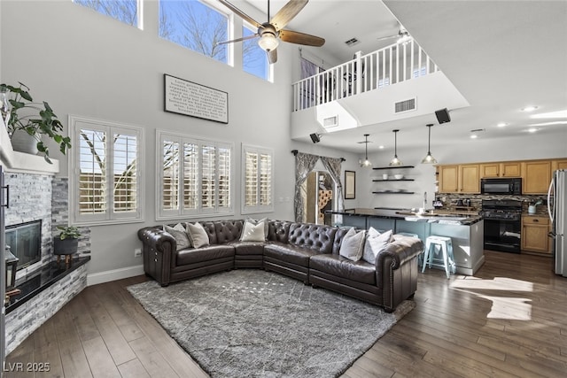 living room featuring baseboards, visible vents, dark wood finished floors, and a fireplace