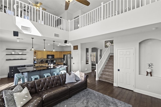 living area with arched walkways, stairway, dark wood finished floors, and visible vents