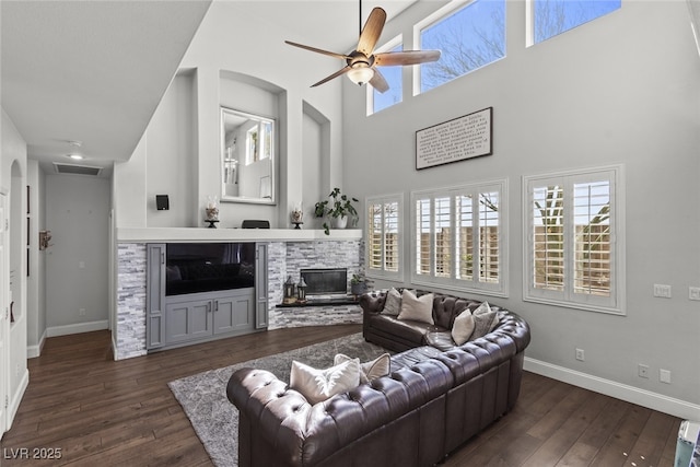 living area featuring dark wood-type flooring, a fireplace, visible vents, and baseboards