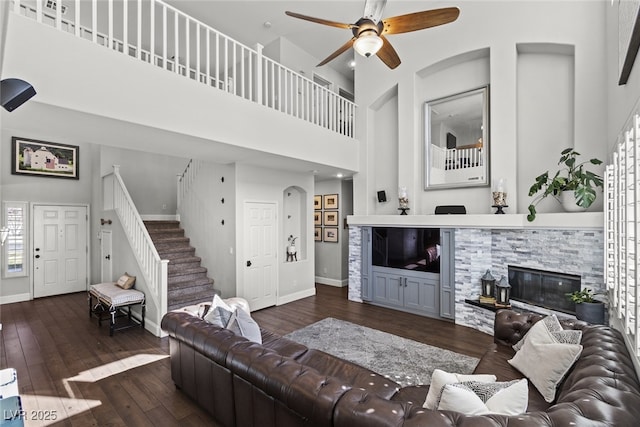 living area featuring wood-type flooring, baseboards, stairway, and a high ceiling