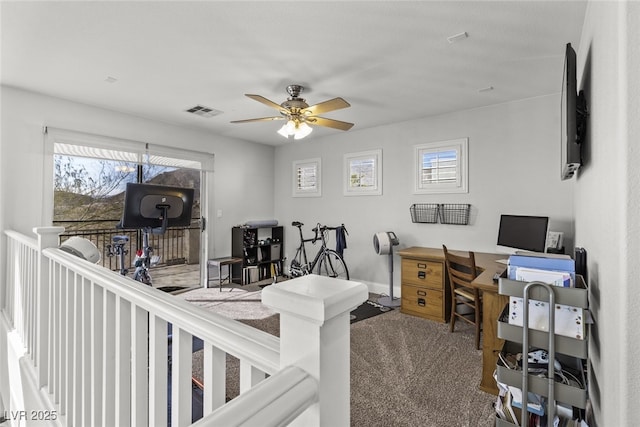 office featuring a ceiling fan, carpet, visible vents, and a healthy amount of sunlight