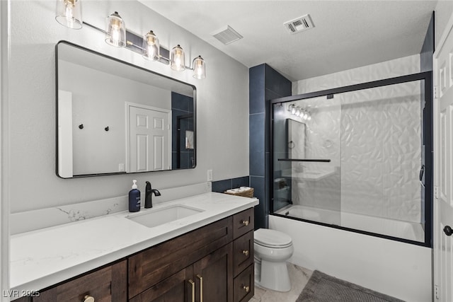 bathroom featuring toilet, visible vents, combined bath / shower with glass door, and vanity