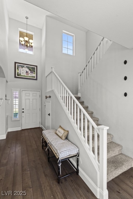 entryway featuring wood-type flooring, a high ceiling, stairway, and baseboards