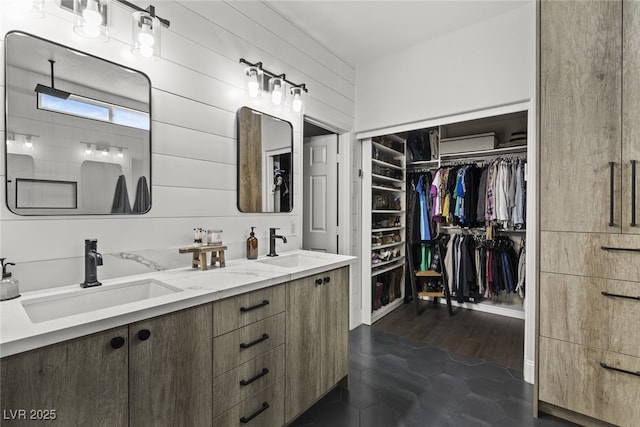 full bath featuring double vanity, a walk in closet, and a sink