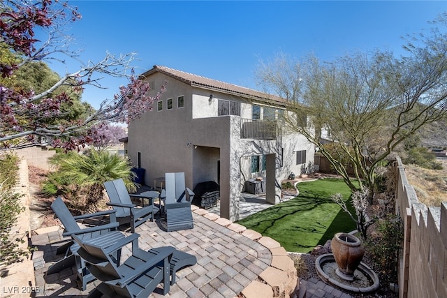 rear view of property featuring a patio area, a fenced backyard, a balcony, and stucco siding