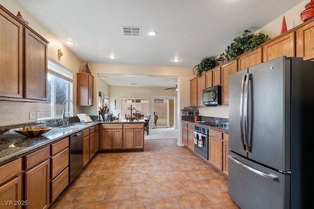 kitchen with dark stone countertops, visible vents, a peninsula, a sink, and black appliances