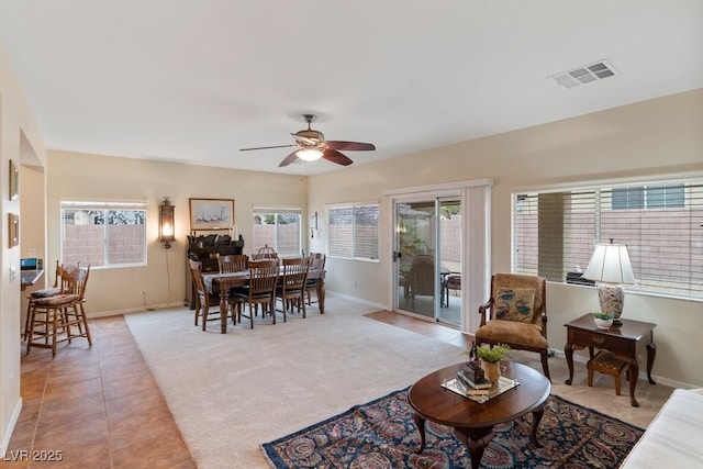 living room featuring visible vents, light tile patterned floors, baseboards, light colored carpet, and ceiling fan